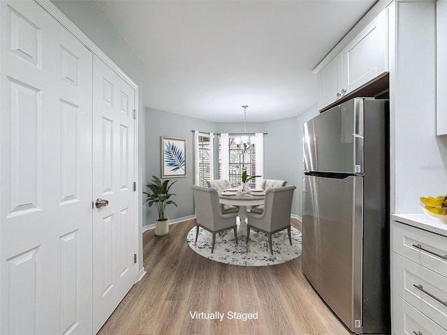 dining room featuring baseboards, light wood-style flooring, and a notable chandelier