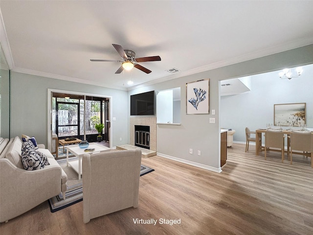 living area featuring light wood finished floors, a glass covered fireplace, visible vents, and baseboards