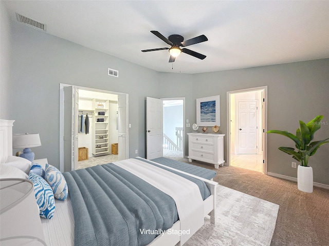 bedroom featuring ceiling fan, a walk in closet, visible vents, and baseboards