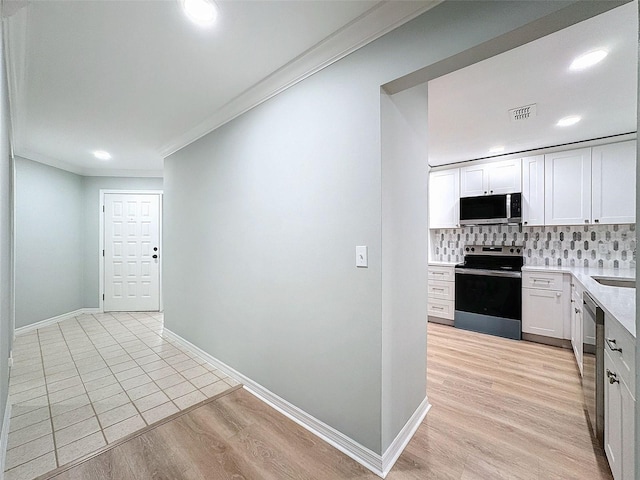 kitchen featuring stainless steel appliances, baseboards, light wood-style floors, ornamental molding, and tasteful backsplash