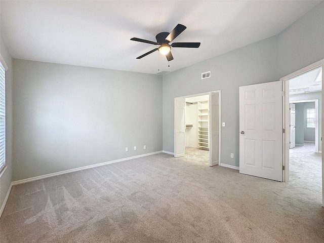 unfurnished bedroom with carpet flooring, visible vents, baseboards, a closet, and a walk in closet