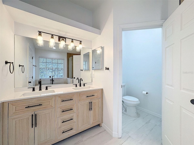 bathroom featuring toilet, marble finish floor, baseboards, and a sink