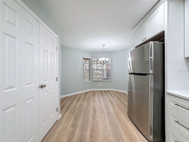 unfurnished dining area with light wood-style floors, baseboards, and a notable chandelier