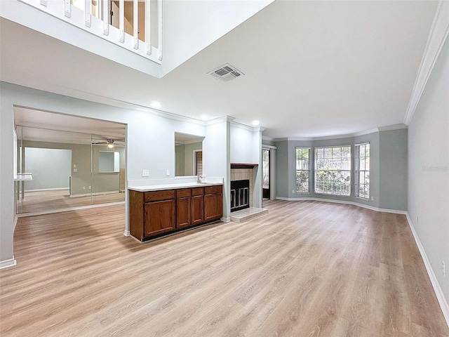 unfurnished living room featuring a fireplace, a ceiling fan, visible vents, baseboards, and light wood-type flooring