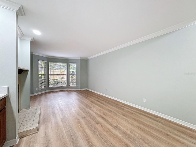 unfurnished living room with light wood finished floors, baseboards, and crown molding