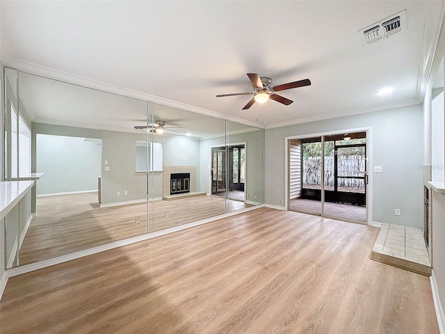 unfurnished living room featuring light wood-style flooring, visible vents, baseboards, a glass covered fireplace, and crown molding