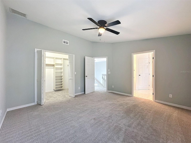 unfurnished bedroom with carpet floors, baseboards, visible vents, and a walk in closet