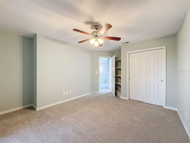 unfurnished bedroom featuring carpet floors, a closet, visible vents, a ceiling fan, and baseboards