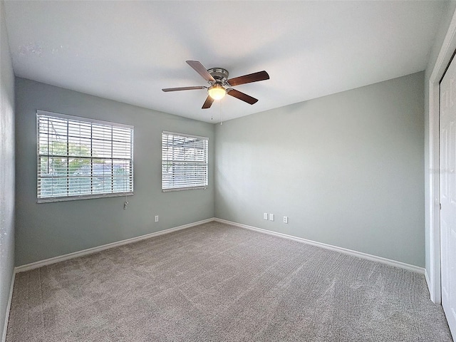 carpeted spare room with ceiling fan and baseboards