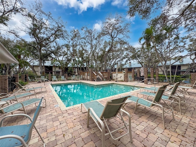 pool with a patio area and fence