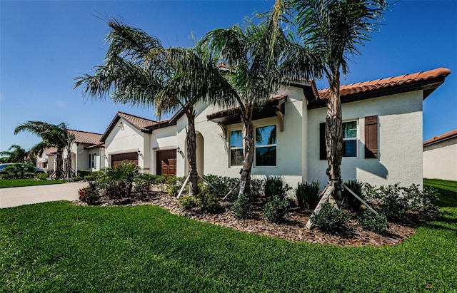 mediterranean / spanish-style house with decorative driveway, stucco siding, a front yard, a garage, and a tiled roof