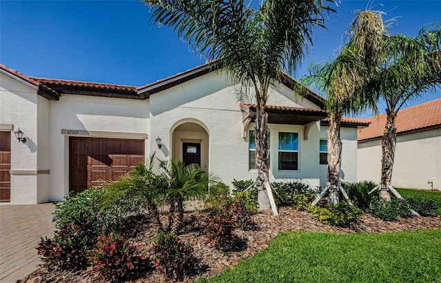 view of front of property with a tile roof, an attached garage, and stucco siding