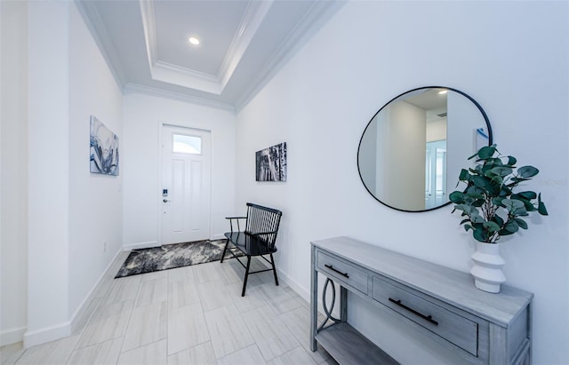 entrance foyer featuring ornamental molding, a tray ceiling, baseboards, and recessed lighting