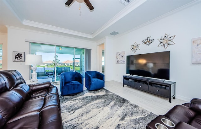 living area with a ceiling fan, visible vents, crown molding, and wood finished floors