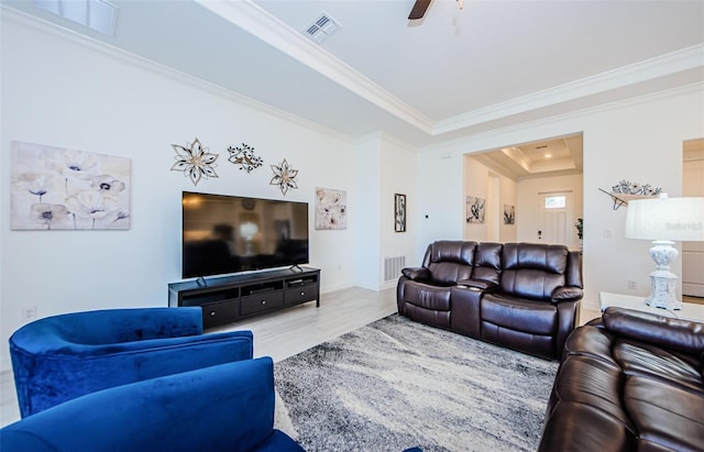 living room featuring ornamental molding, ceiling fan, a tray ceiling, and visible vents