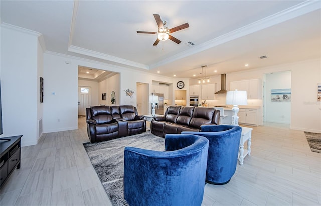 living room with baseboards, visible vents, ornamental molding, and a raised ceiling