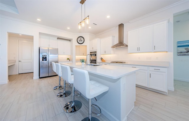 kitchen featuring a center island with sink, a kitchen breakfast bar, wall chimney range hood, gas stovetop, and stainless steel refrigerator with ice dispenser