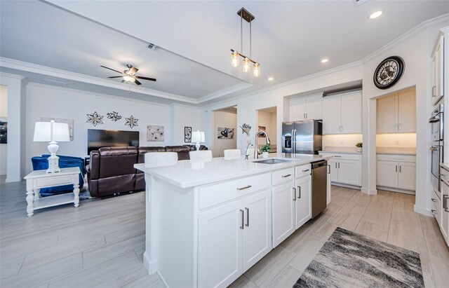 kitchen featuring a kitchen island with sink, a sink, light countertops, appliances with stainless steel finishes, and pendant lighting