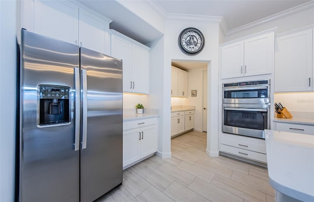 kitchen with white cabinetry, ornamental molding, stainless steel appliances, and light countertops