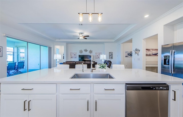 kitchen featuring appliances with stainless steel finishes, open floor plan, ornamental molding, light countertops, and a sink