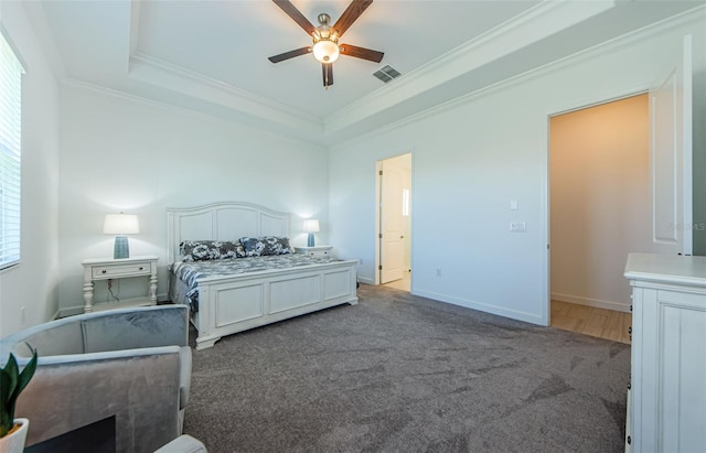 bedroom featuring carpet floors, a raised ceiling, visible vents, and crown molding