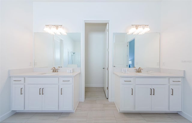 full bath with a sink, baseboards, and two vanities