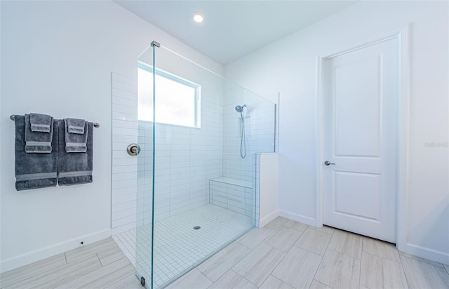 full bathroom with tiled shower and baseboards