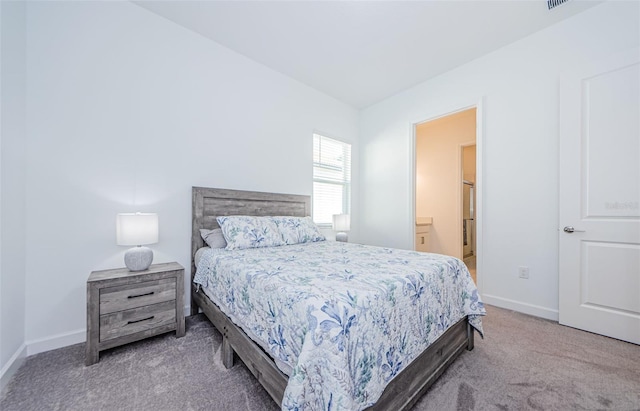 carpeted bedroom featuring ensuite bath, visible vents, and baseboards