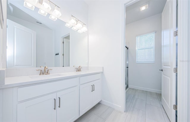 full bath with a stall shower, a sink, baseboards, and double vanity