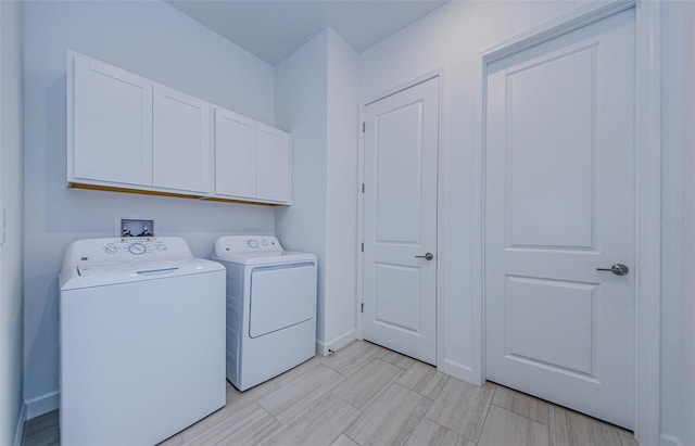 clothes washing area with cabinet space, independent washer and dryer, and baseboards