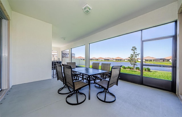 sunroom / solarium with a residential view, a healthy amount of sunlight, visible vents, and a water view