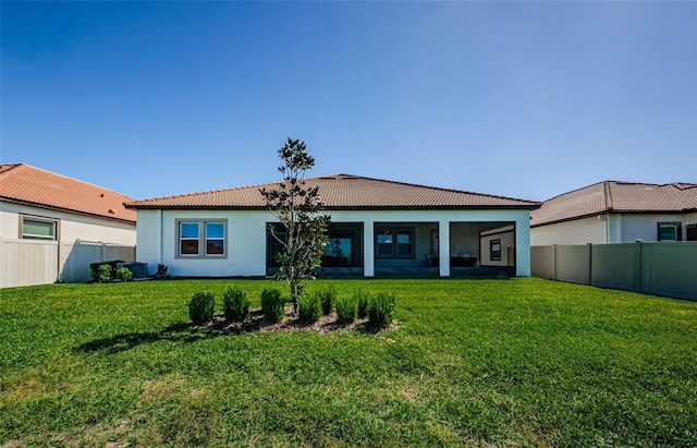 rear view of property featuring a fenced backyard, a yard, and a tiled roof