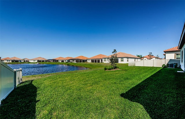 view of yard featuring a water view, fence, and a residential view