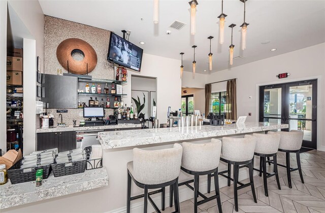 kitchen with a breakfast bar, french doors, decorative light fixtures, visible vents, and backsplash