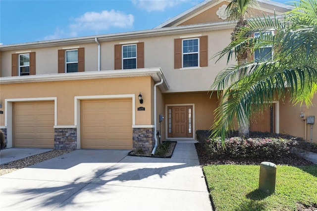 view of property featuring stone siding, a garage, driveway, and stucco siding