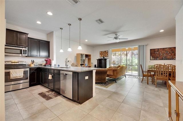 kitchen with visible vents, a sink, open floor plan, appliances with stainless steel finishes, and crown molding