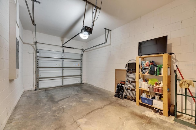 garage featuring concrete block wall and a garage door opener