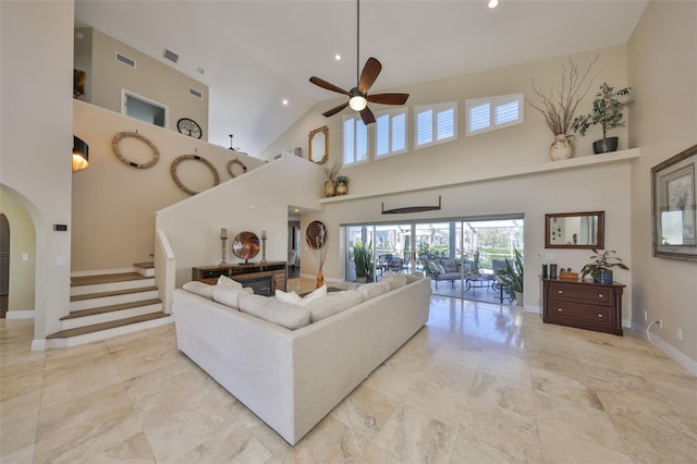 living area featuring arched walkways, visible vents, a ceiling fan, stairs, and baseboards