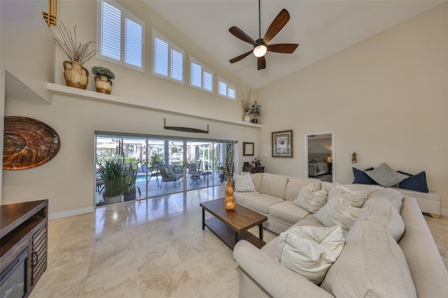 living area with high vaulted ceiling, ceiling fan, and baseboards