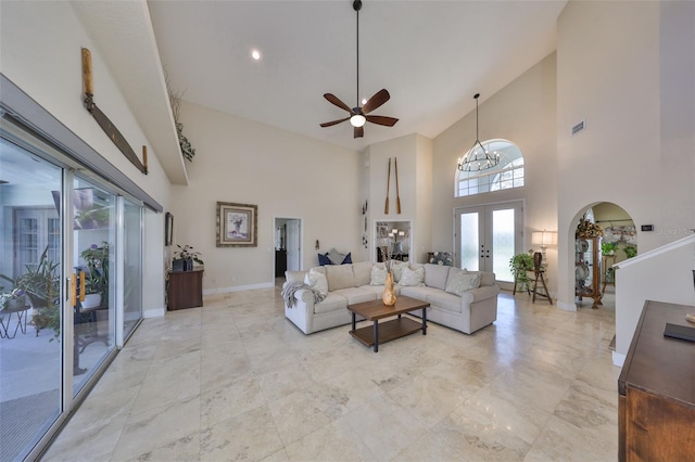 living room with arched walkways, a towering ceiling, visible vents, baseboards, and french doors