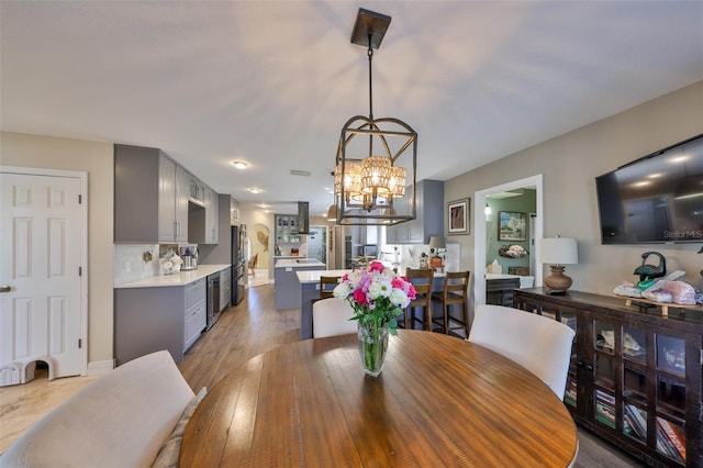 dining area featuring beverage cooler, light wood-type flooring, and an inviting chandelier