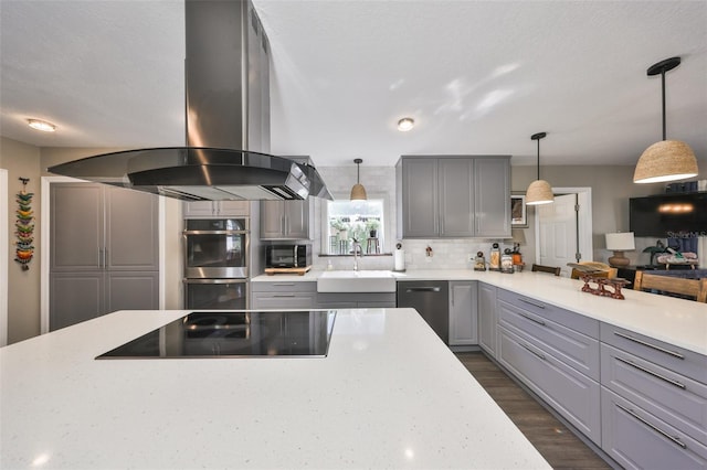 kitchen with double oven, gray cabinetry, a sink, and island range hood