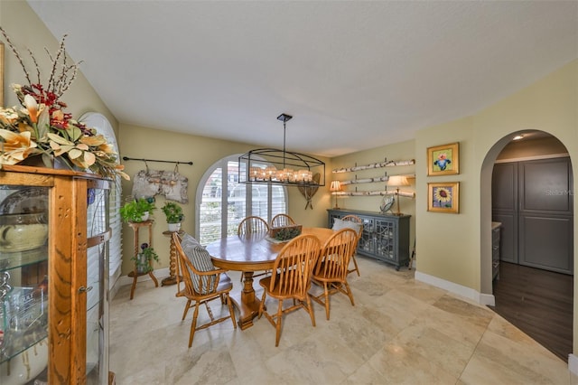 dining room with arched walkways, baseboards, and a notable chandelier