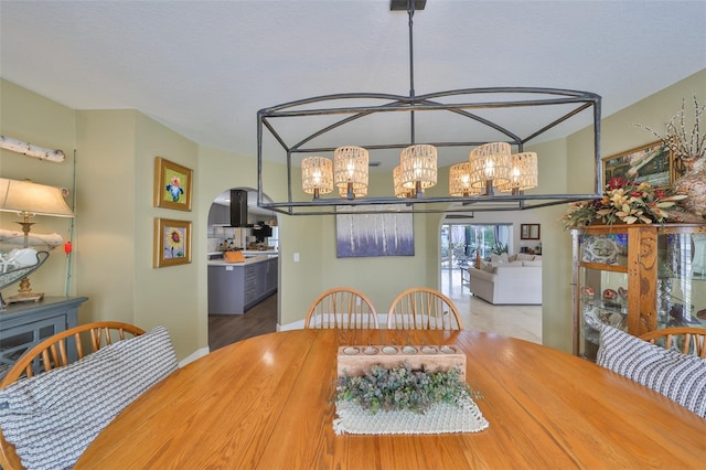 dining space featuring arched walkways and a chandelier