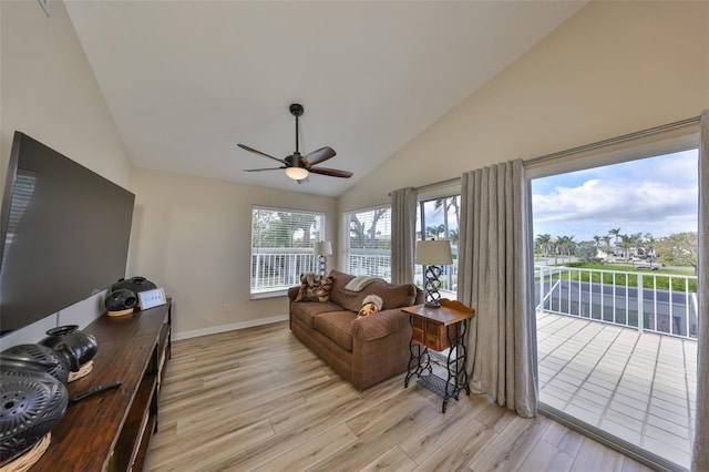 interior space featuring a ceiling fan, baseboards, high vaulted ceiling, and light wood finished floors