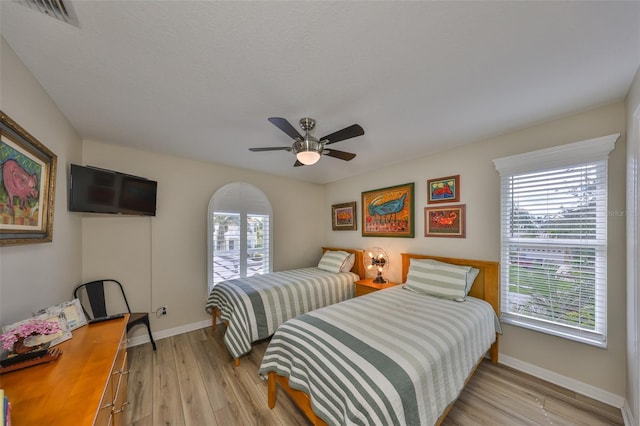 bedroom with a ceiling fan, baseboards, visible vents, and light wood finished floors