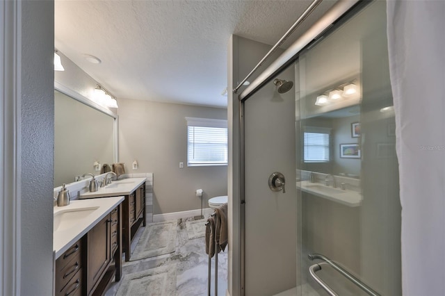 full bathroom featuring a textured ceiling, toilet, vanity, baseboards, and a shower stall