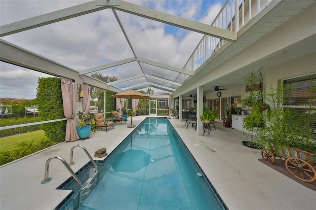 view of pool featuring a patio area, a swimming pool, glass enclosure, and a ceiling fan