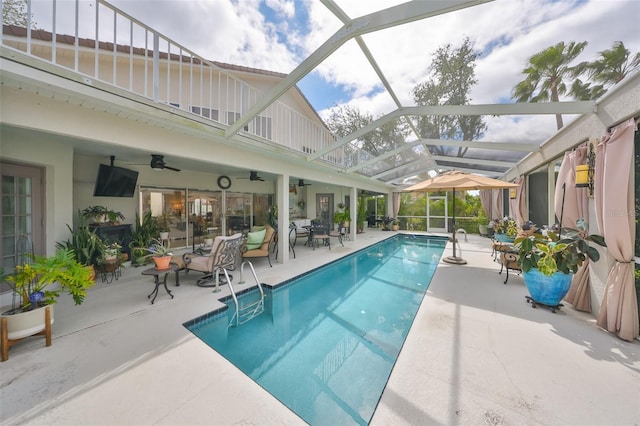 outdoor pool with a lanai, a ceiling fan, and a patio