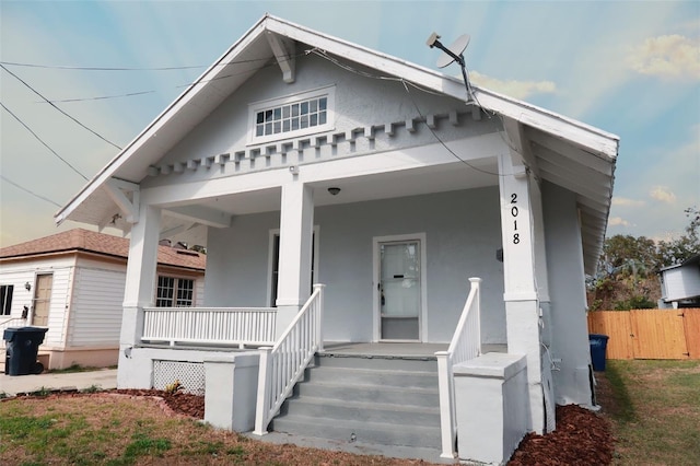 view of front of home featuring fence, a porch, and stucco siding